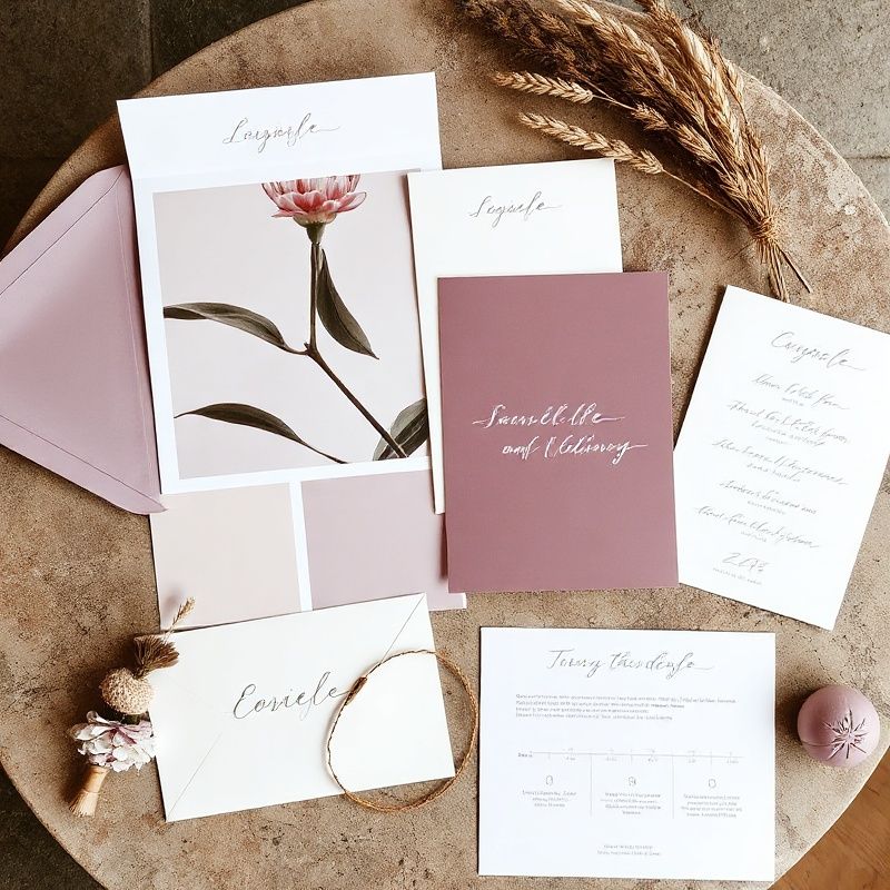 Flat-lay of bespoke wedding planning materials — violet mood board, cream stationery, and a hand-written timeline
